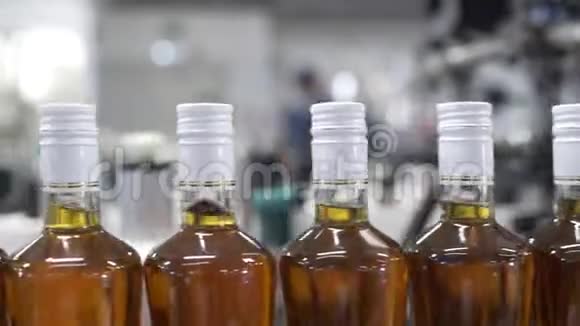 玻璃瓶与白色箔密封充满酒精沿输送线移动与控制面板在工厂视频的预览图
