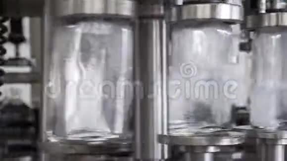 酒精饮料的生产和装瓶在酒厂的玻璃瓶里溢出伏特加传送带上的玻璃瓶视频的预览图
