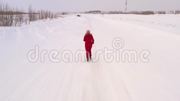 女性在白雪覆盖的雪堆和树木中沿着一条冬天的道路奔跑这是从无人驾驶飞机上最高的景色视频的预览图