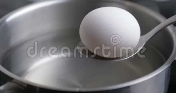 汤勺上放一个白生鸡蛋用水煮鸡蛋热水中的鸡蛋视频的预览图