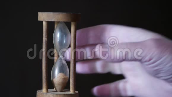 一只雄性的手在棕色的深色背景上翻转一个老式沙漏独特的计时器视频的预览图