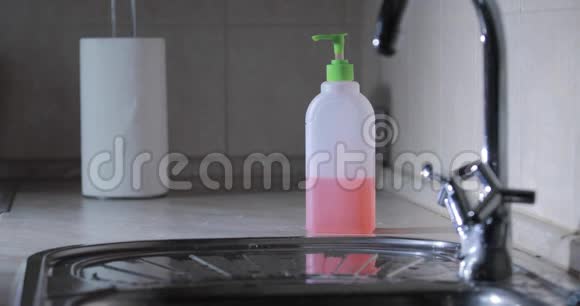 男士在水中洗手用洗手液按压瓶胶在背景上消毒双手视频的预览图