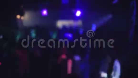 在彩色聚光灯和激光的照射下一群人在夜总会的舞池里跳舞视频的预览图