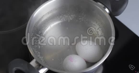 两个生的白鸡蛋在不锈锅中煮在沸水中健康的天然蛋白质早餐烹饪鸡蛋是视频的预览图