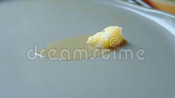 黄色的酥油在灰色的热油炸锅上移动和融化慢点视频的预览图