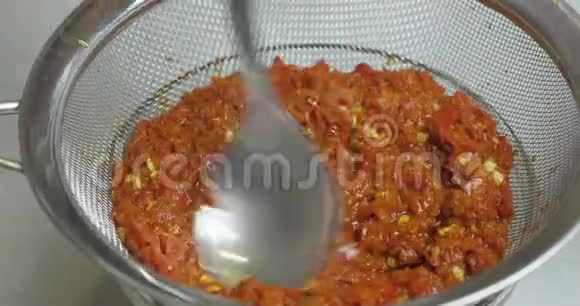 通过蒸煮后的一个筛子过滤均匀的红辣椒质量得到一个热辣椒酱蔬菜炖菜视频的预览图