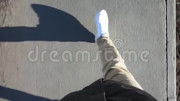 阳光明媚的一天穿着白色运动鞋的人穿着牛仔裤在人行道上散步第一人称视频视频的预览图