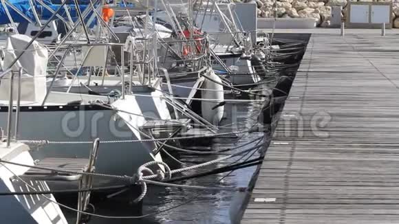 白色游艇和停泊在码头的船只木制码头阳光明媚的一天在海滨村视频的预览图