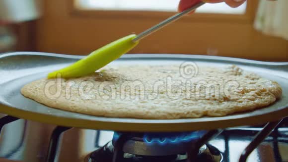 黄油刷在厨房的热锅煤气炉上涂上煎饼慢速特写视频的预览图