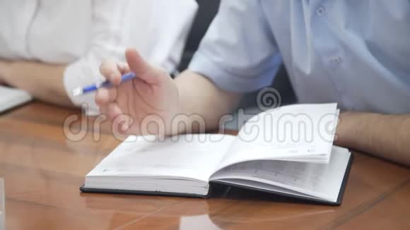 男性手握笔在公司会议的办公桌面上手写商务报告做好书面文件的记录视频的预览图