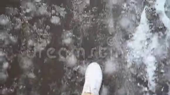 白色运动鞋行走在湿沥青人行道上的雪地POV视频视频的预览图