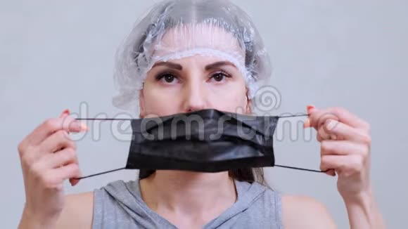 戴一次性帽子的女性患者戴上黑色防护面罩卫生概念防止细菌和视频的预览图