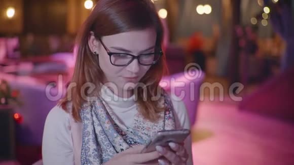 有魅力的女孩戴着眼镜拿着手机和社交网络上的朋友聊天享受早晨的放松视频的预览图
