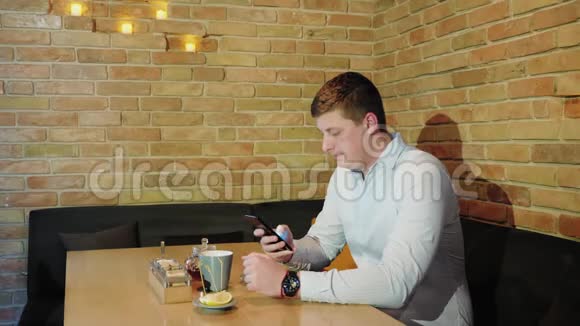 一个拿着电话的人坐在咖啡馆里视频的预览图