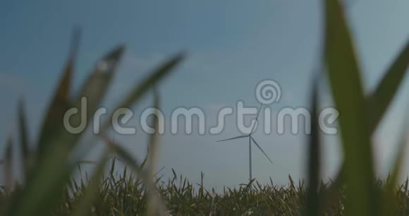 蓝天绿草背景下旋转风车风力发电清洁和可再生能源解决方案风力涡轮机视频的预览图