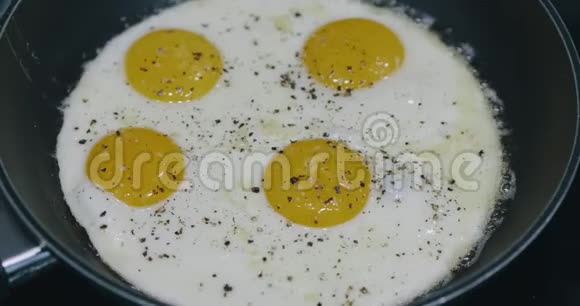 在黑金属锅里煮四个煎蛋煎锅中四个鸡蛋的早餐食品准备上景视频的预览图