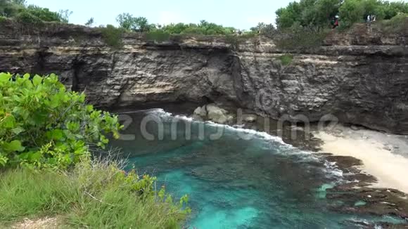美丽的景色从悬崖到海浪撞击在绿色植物背景上的海岩石断滩视频的预览图