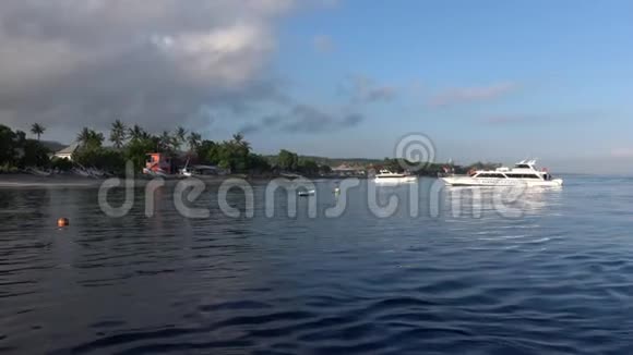 白色摩托艇游客从印度尼西亚巴厘岛出发在阳光明媚的印度尼西亚努沙佩尼达向热带岛屿海岸移动视频的预览图