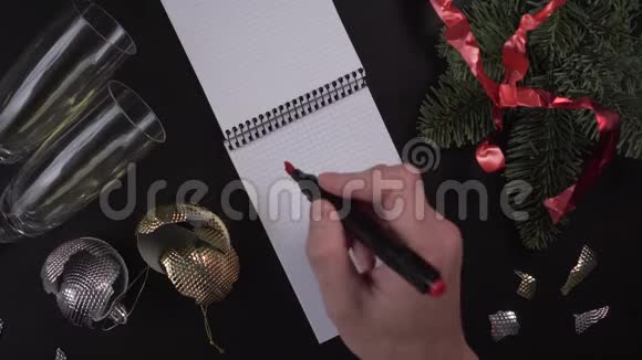 一个年轻人在笔记本上写下了2020年目标这几个字放在一张木桌上桌上围着圣诞庆典的主题视频的预览图