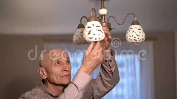 集中精力的老人穿着格子衬衫毫无光泽的灯泡视频的预览图