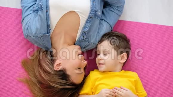 妈妈和儿子躺在家里的地板上一个快乐的妈妈和她儿子的视频肖像视频的预览图