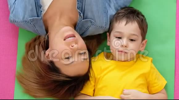 妈妈和儿子躺在家里的地板上一个快乐的妈妈和她儿子的视频肖像视频的预览图