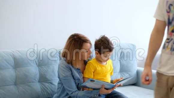 妈妈和儿子正坐在客厅的绿松石沙发上看书视频的预览图