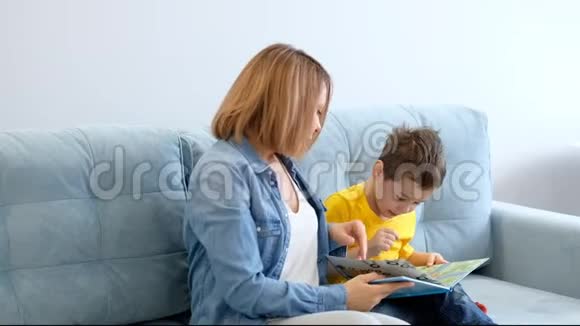妈妈和儿子正坐在客厅的绿松石沙发上看书视频的预览图
