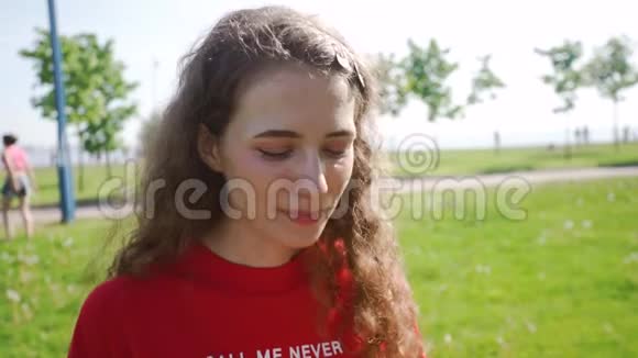 卷曲迷人的女孩吹在蒲公英上年轻漂亮的女人许了个愿穿着红色T恤的女士视频的预览图