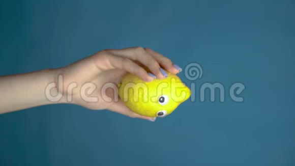 柠檬的眼睛在一个女人的手闭上柠檬在蓝色背景上环顾四周垂直视频视频的预览图