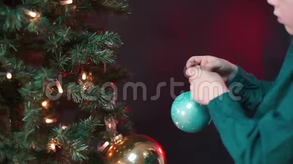 一个小学生把一个新年玩具一个球放在圣诞树上视频的预览图