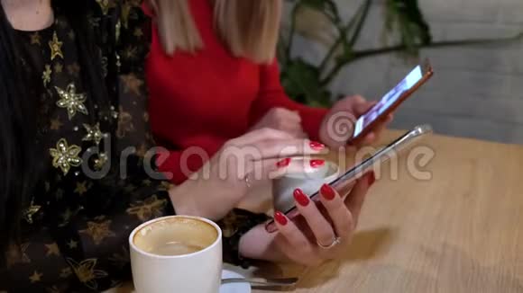 两位年轻女性在咖啡厅使用智能手机无线在线浏览互联网女性手拿装置视频的预览图