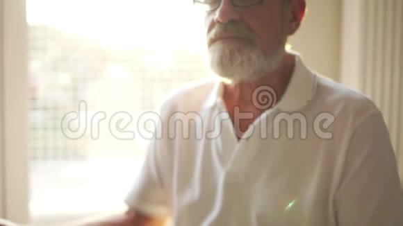 一位年长的灰胡子男子坐在地板上的莲花位置的近距离肖像瑜伽课程精神视频的预览图