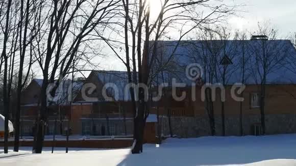 冬季乡村景观在新的木屋的背景下雪在阳光下落下闪闪发光视频的预览图