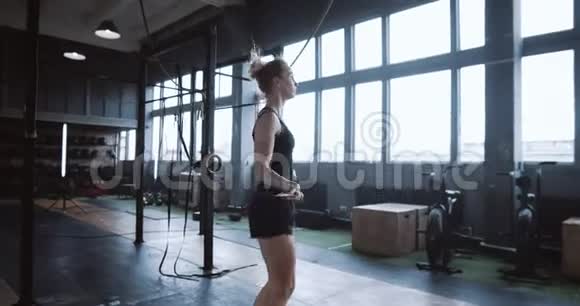 侧面观看美丽的年轻白种人妇女锻炼与跳绳在健身房慢动作积极健康的生活方式视频的预览图