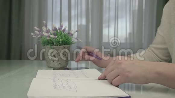 年轻女子用钢笔特写在记事本页上手写视频的预览图