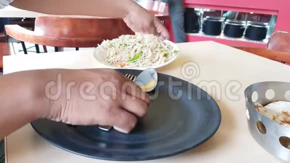 一双手在一家餐馆里把肉卷从一个白色的盘子拿到一个黑色的盘子视频的预览图