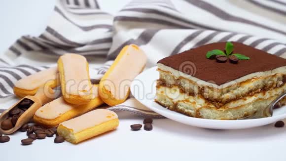 泰拉米苏甜点部分在陶瓷盘子萨维亚迪饼干和咖啡豆隔离在白色视频的预览图