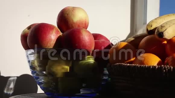 阳台桌上的橘子香蕉和苹果阳光明媚的天气细节柳条和玻璃碗视频的预览图