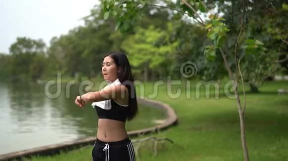年轻女性在自然公园慢跑前伸展肌肉视频的预览图