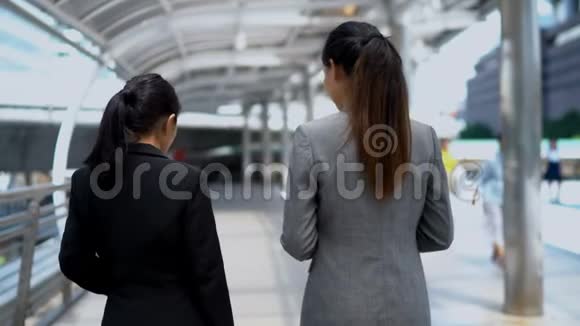 两个年轻的女商人在桥边散步聊天视频的预览图