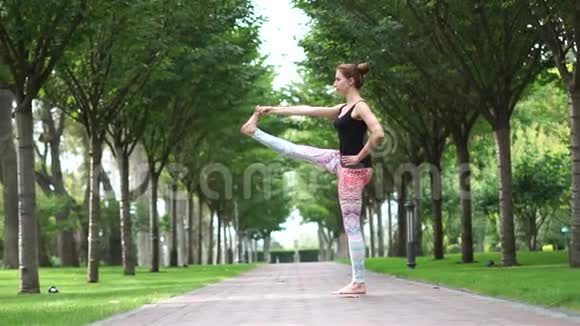在公园小巷里慢动作做瑜伽的漂亮女孩视频的预览图