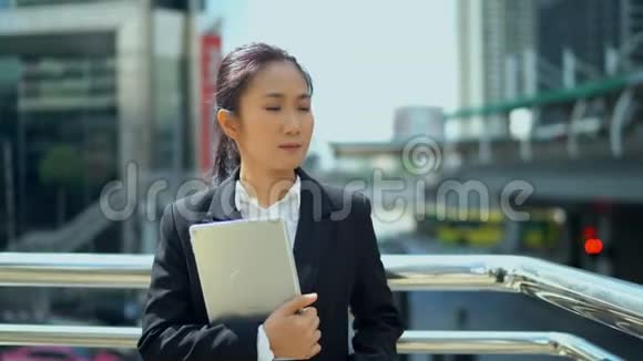 年轻的女商人抱着笔记本电脑走路视频的预览图