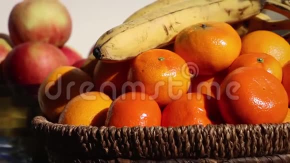 新鲜水果橘子苹果玻璃中的香蕉和柳条碗细节视频的预览图