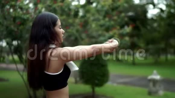 年轻漂亮的女人在自然公园锻炼前伸展身体视频的预览图