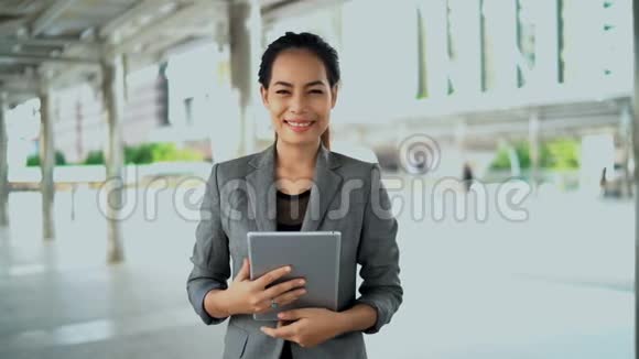 年轻工作妇女站在室外使用平板电脑视频的预览图