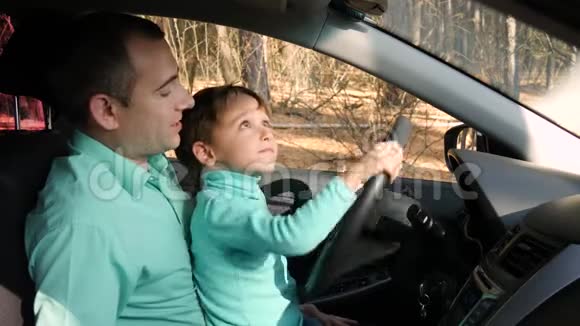 一个快乐的父亲坐在车里和他的儿子玩那个男孩假装开汽车转动方向盘家庭视频的预览图