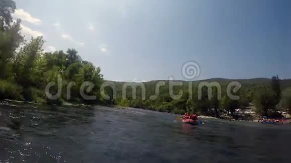 一群穿着漂流装备的人在橡皮艇上漂浮在山河上视频的预览图