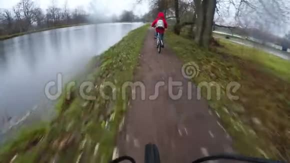 两个骑自行车的人骑在湖边泥泞的乡间小路上视频的预览图