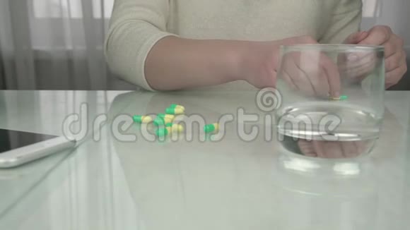 带美甲的女士手数桌上的黄绿色药丸视频的预览图